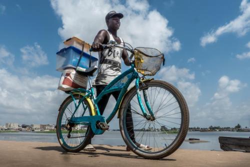 [Entrée] Intermodalité... Un cycliste débarque d'une pinasse pour poursuivre son périple dans le quartier d'Adjahui